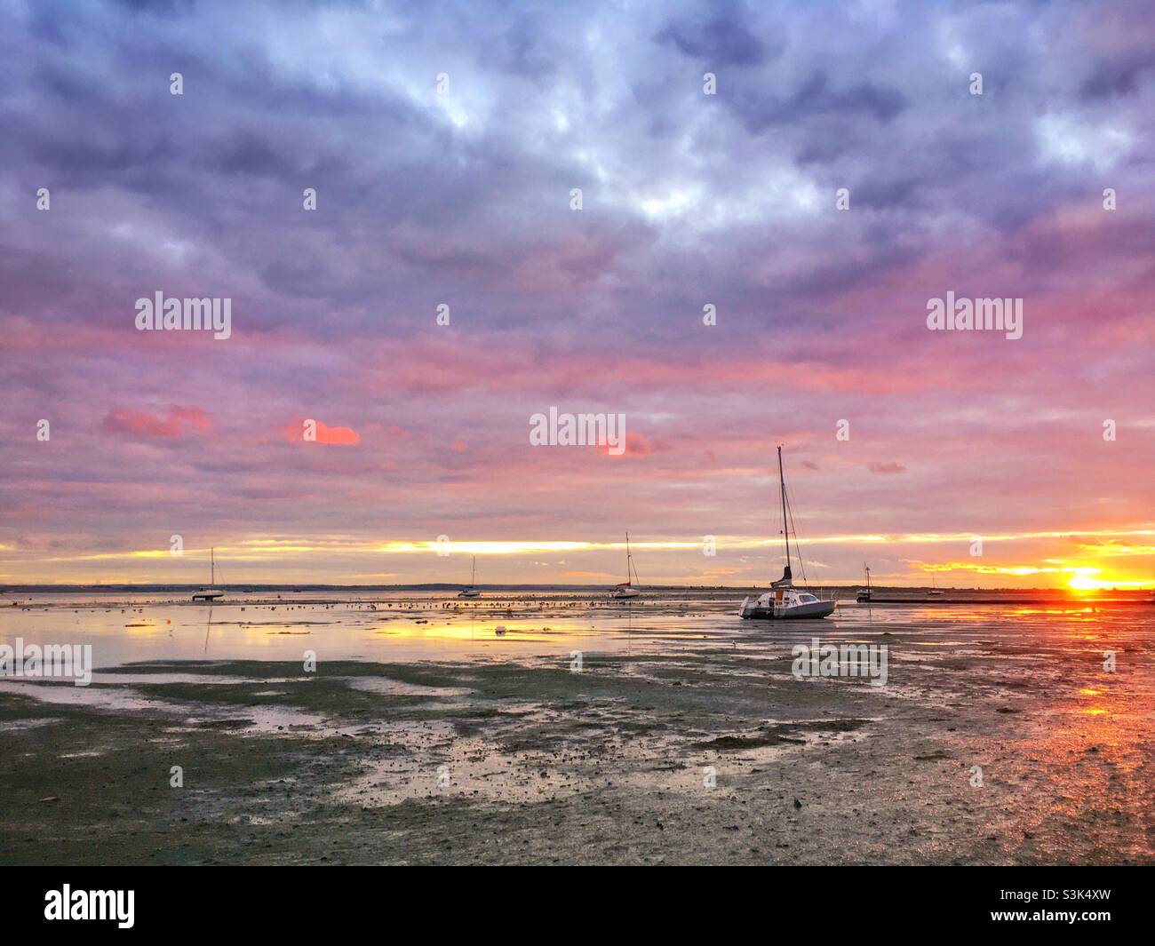 Coucher de soleil à marée basse à Leigh-on-Sea avec de petits bateaux assis sur la boue de l'estuaire de la Tamise Banque D'Images