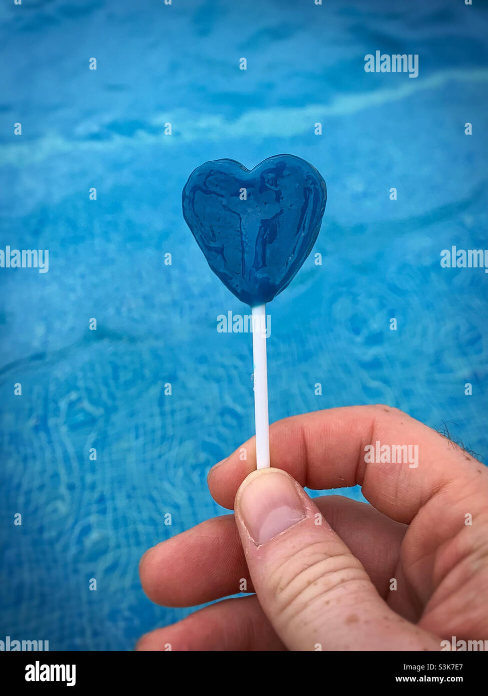 Bleu amour coeur lollipop contre un fond bleu de piscine.Cassé.Désir.Romance Banque D'Images