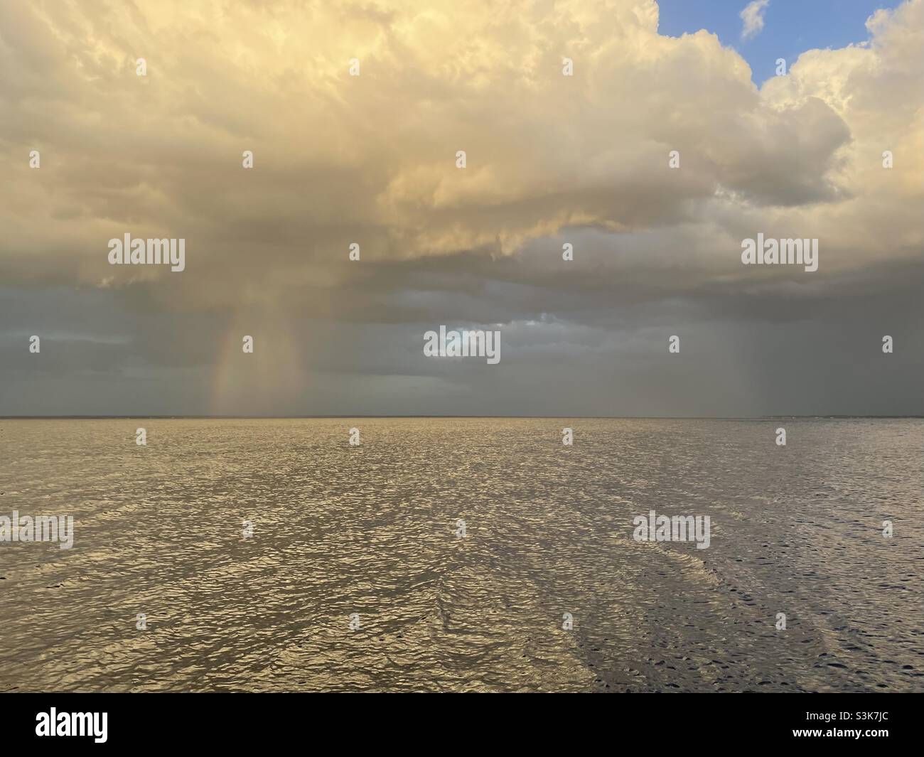 Des nuages d'or spectaculaires orageux avec des rayons au-dessus de l'eau de la baie Banque D'Images