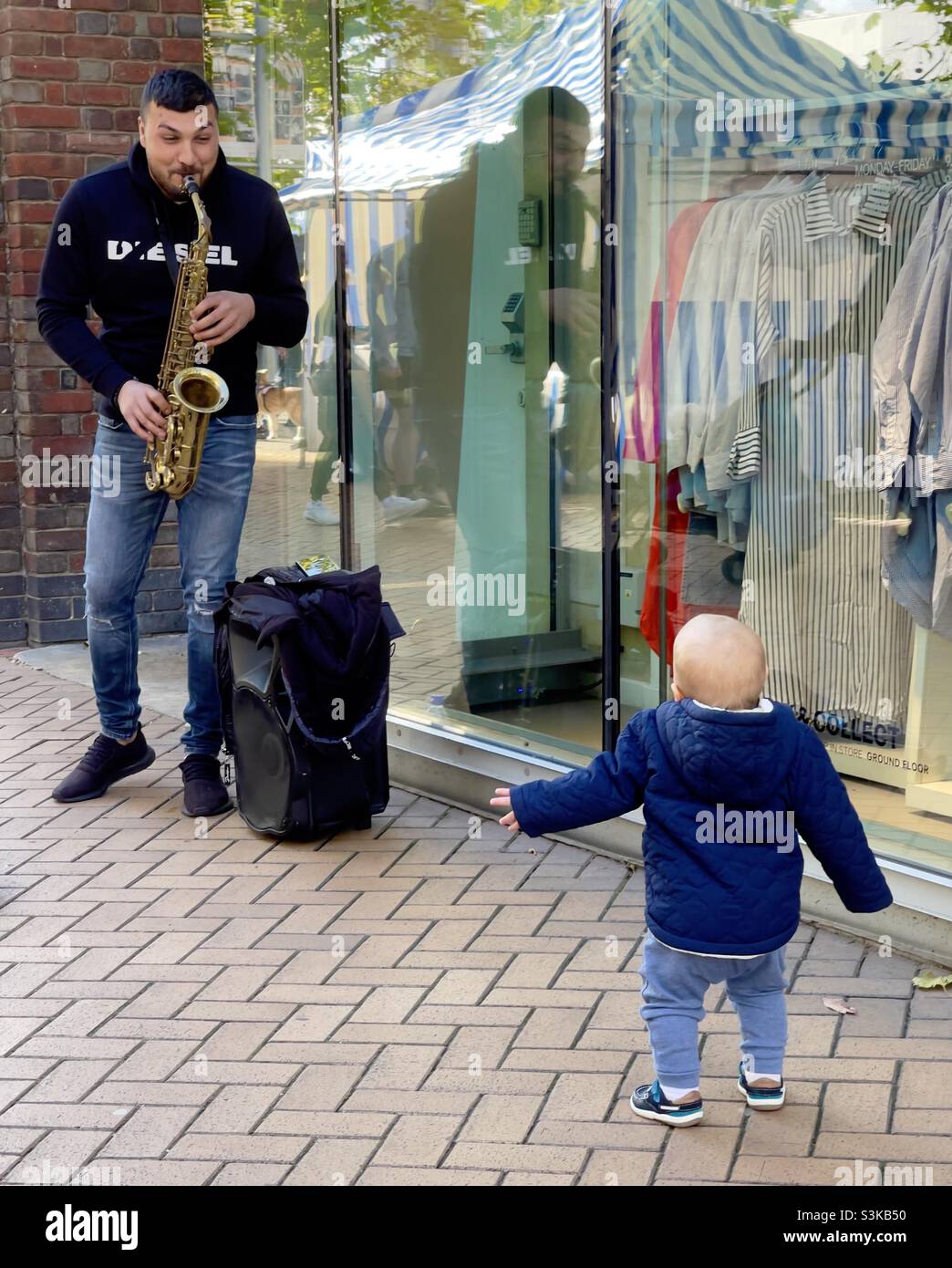 Bébé dansant à la musique de saxophone de rue Banque D'Images