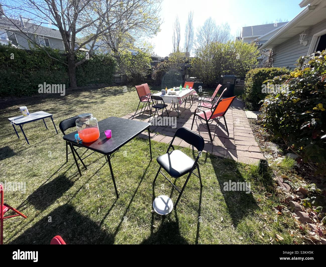 Un patio et une arrière-cour en été après une famille se réunir et faire la fête.Le nettoyage est encore incomplet avec des tables, des chaises, des restes de nourriture et de boissons. - Image de stock capturée avec un smartphone