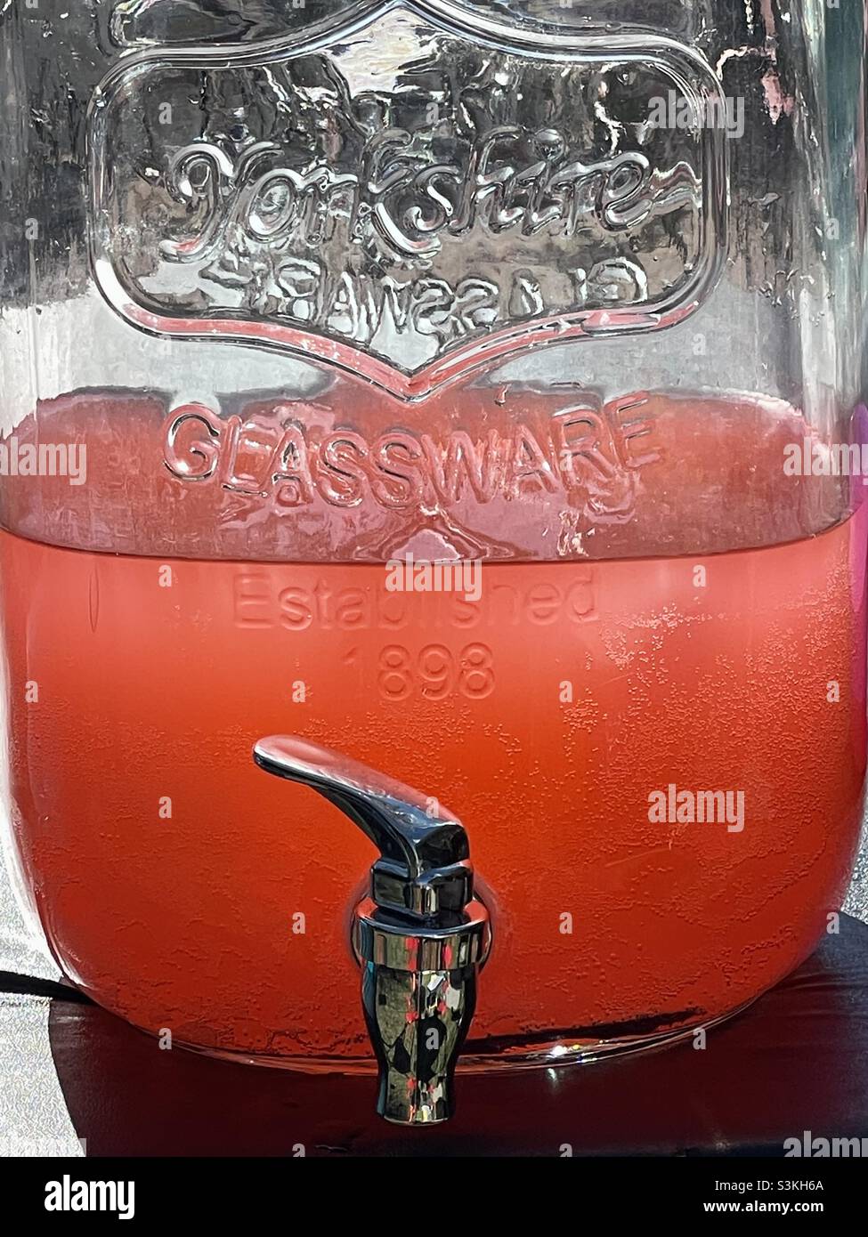 Un distributeur de boissons en verre est rempli de limonade rose pour une  fête de famille d'été Photo Stock - Alamy