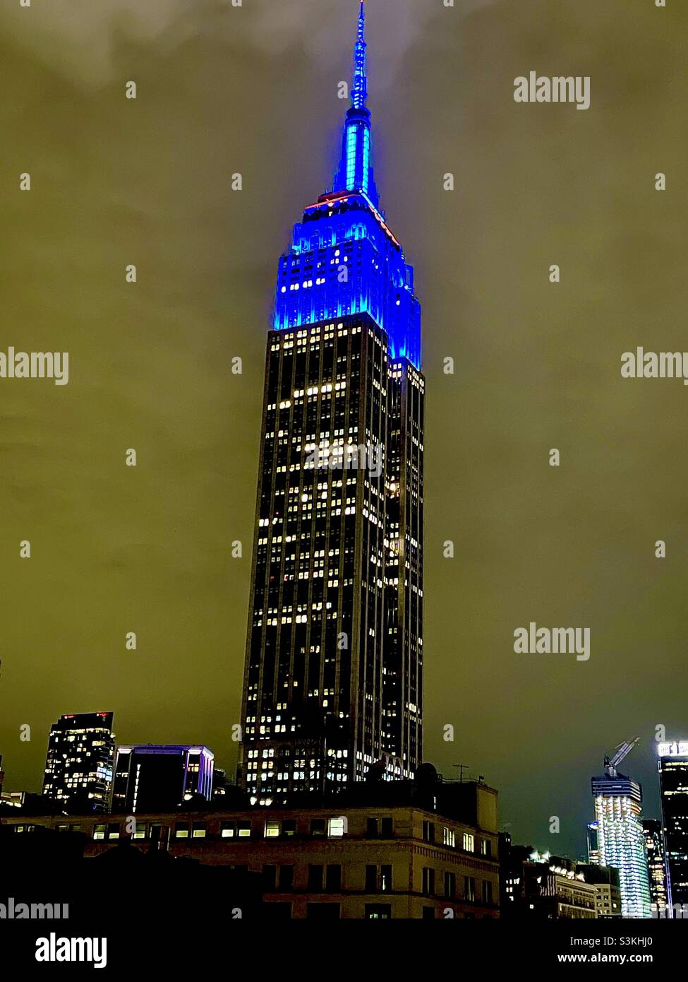 Lumières bleues vives au sommet de l'Empire State Building lors d'une nuit nuageux à New York - Image de stock capturée avec un smartphone