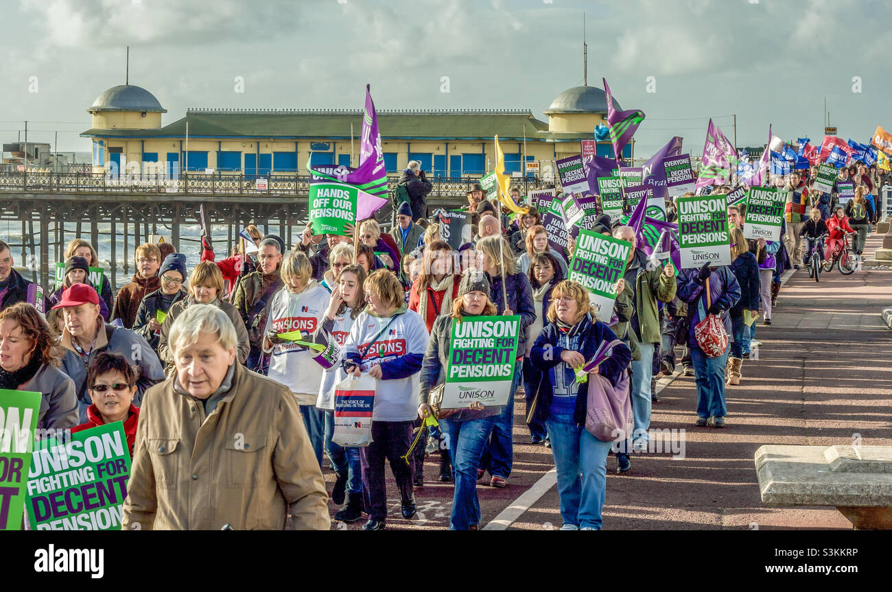 Un grand groupe de manifestants défilant le long du front de mer de Hastings, près de la jetée lors d'une manifestation anti-austérité en novembre 2011 Banque D'Images
