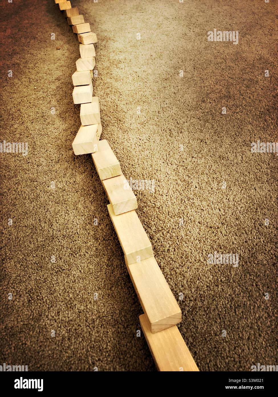 Jouets briques en bois tombés dans une ligne sur un tapis Banque D'Images