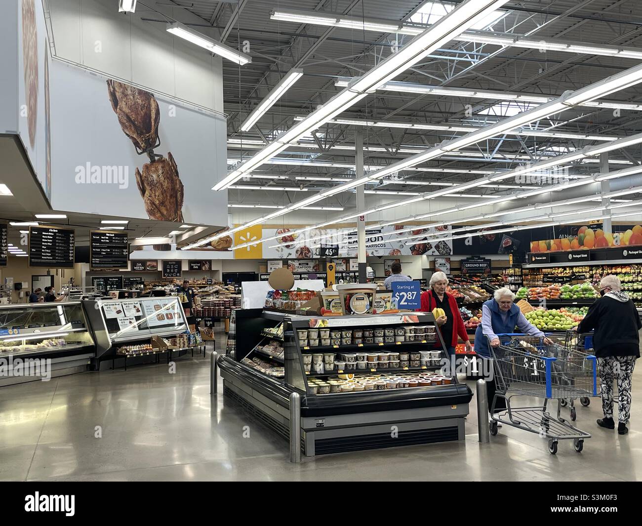 À l'intérieur d'un super centre Walmart dans l'Utah, aux États-Unis.Les étalages de nourriture et les étagères d'articles à vendre sont visibles dans le grand magasin et les acheteurs peuvent être vus faire leurs achats. - Image de stock capturée avec un smartphone