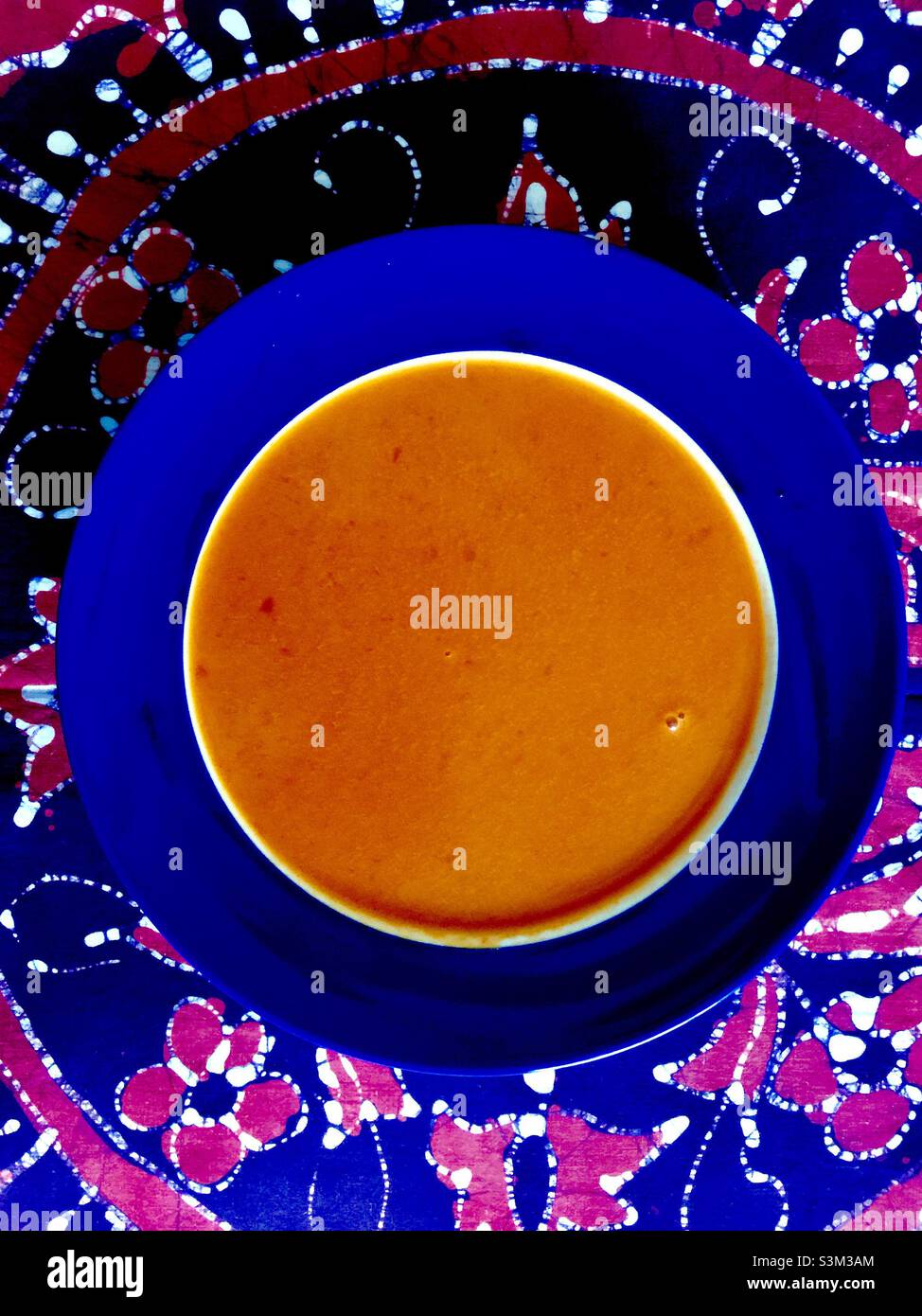Un repas très confortable : un bol de soupe chaude à la tomate, une combinaison colorée d'orange, de bleu et de rouge. Banque D'Images