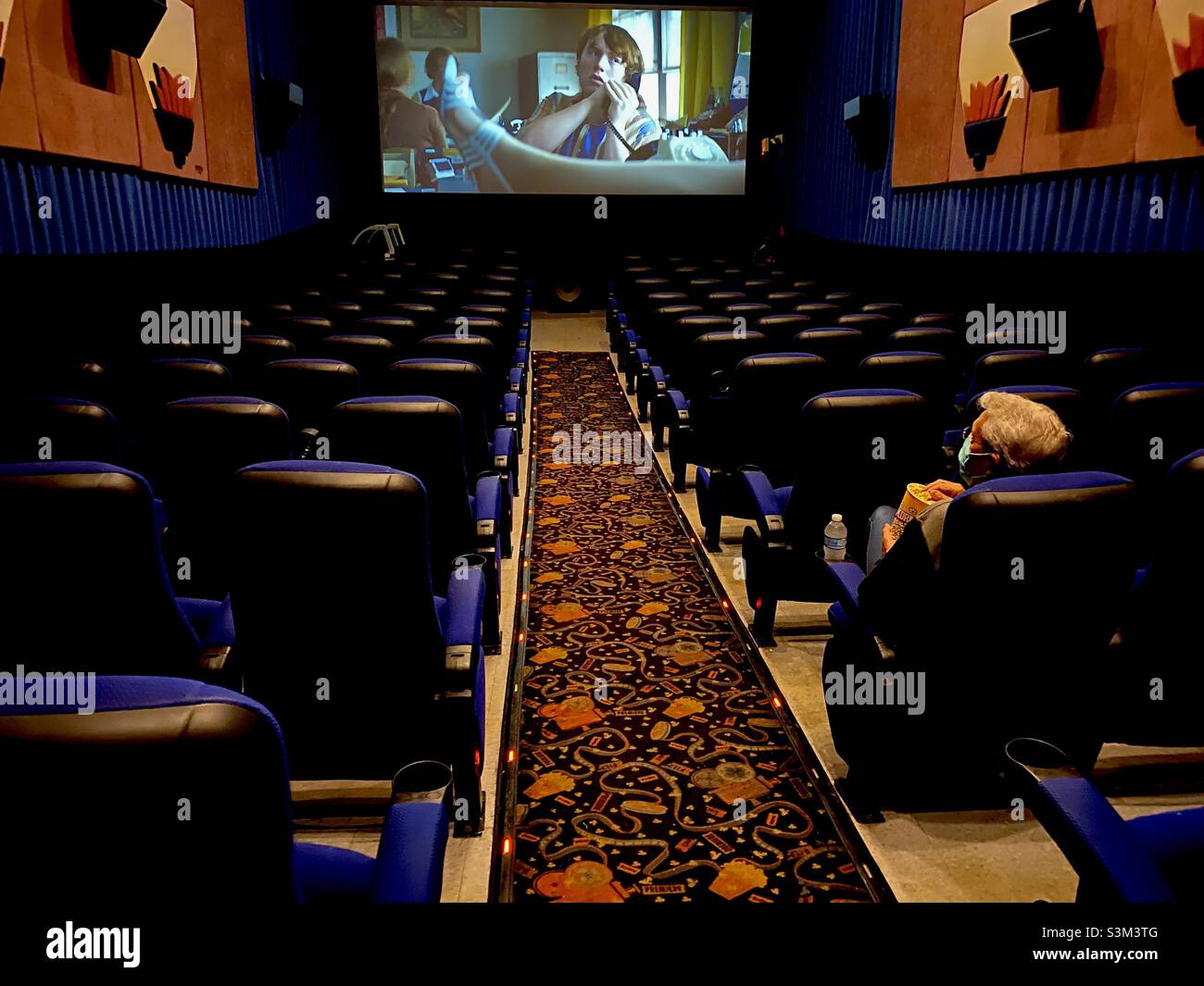 Homme solitaire assis dans un cinéma vide pendant la pandémie COVID-19 en 2021. Banque D'Images