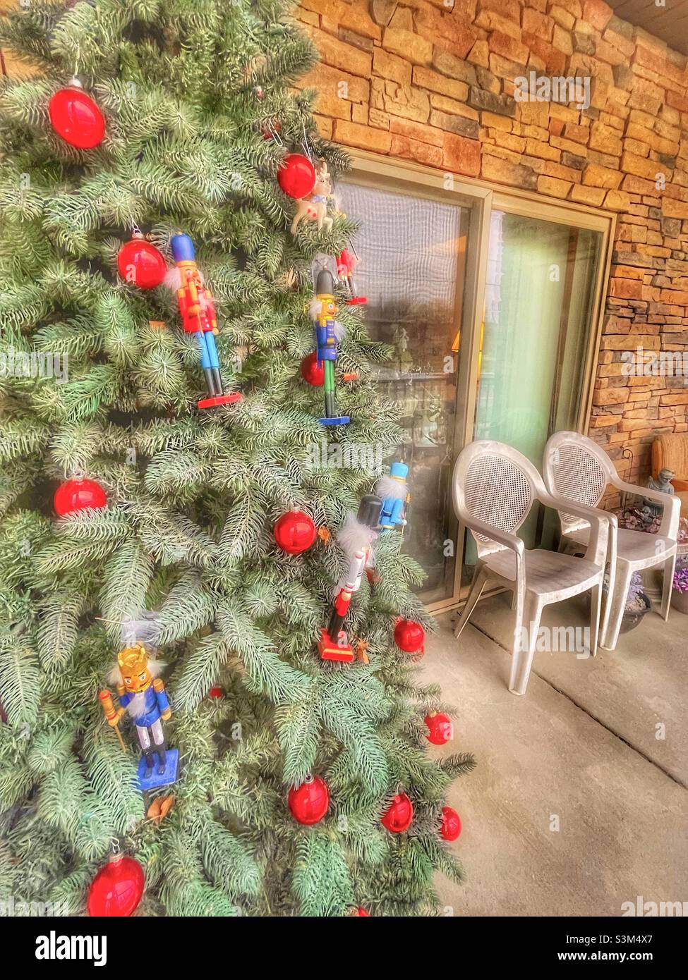 Un petit patio d'appartement, dans l'Utah, aux États-Unis, pendant la saison des fêtes, a un arbre de Noël décoré avec des ornements rouges et des casse-noisettes. - Image de stock capturée avec un smartphone