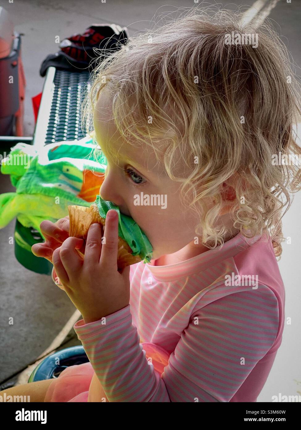 Petite fille d'anniversaire de deux ans mangeant un cupcake avec glaçage vert. Banque D'Images