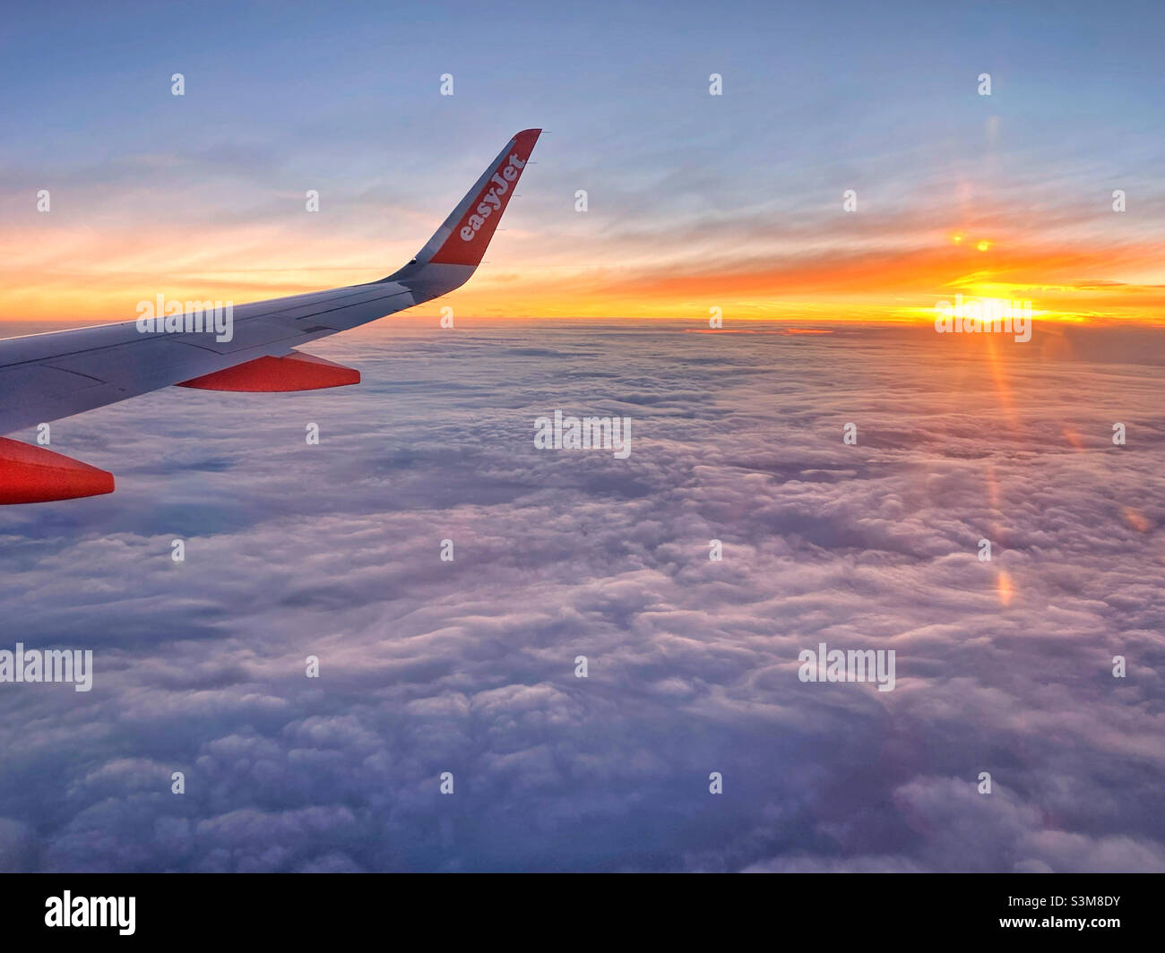 Lever de soleil au-dessus des nuages.Vue depuis une fenêtre d'avion easyJet au-dessus des nuages, quelque part au-dessus de l'Europe.Photo ©️ COLIN HOSKINS. Banque D'Images