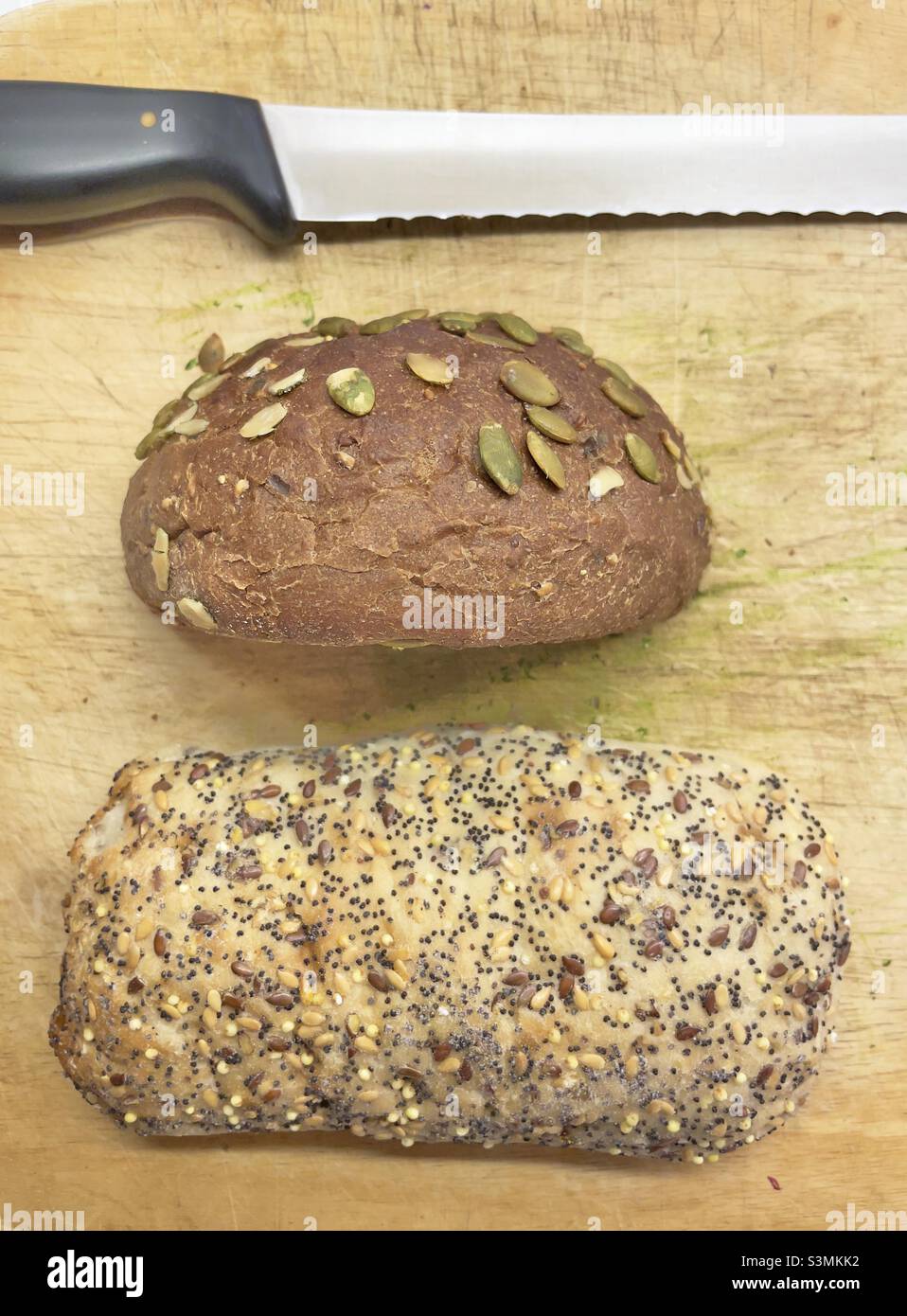 Une planche à pain avec un couteau à pain et deux sortes de pain brun Banque D'Images