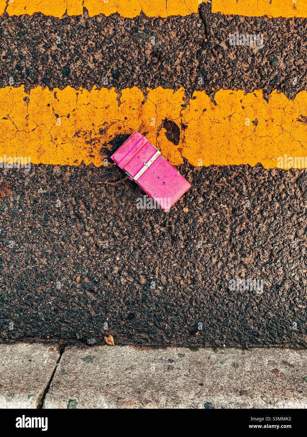 Tapis rose posé sur la route à côté de lignes jaunes doubles - Image de stock capturée avec un smartphone