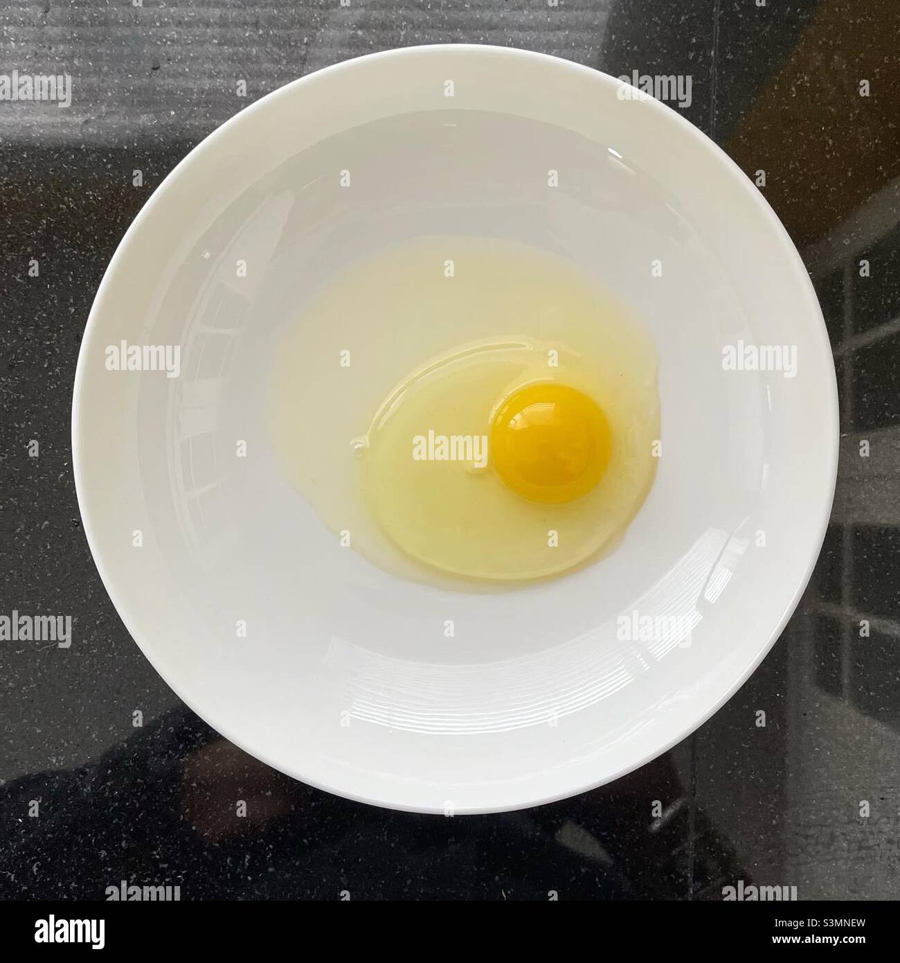 Œuf de poulet fissuré dans un bol blanc - Image de stock capturée avec un smartphone