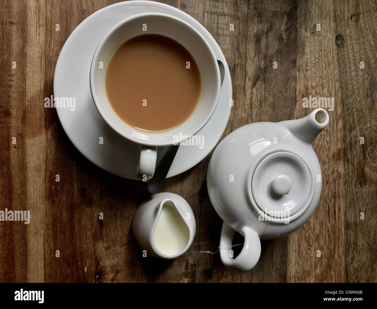 Une tasse de thé et une casserole de thé avec du lait sur une table rustique en bois.Prise en Angleterre Banque D'Images