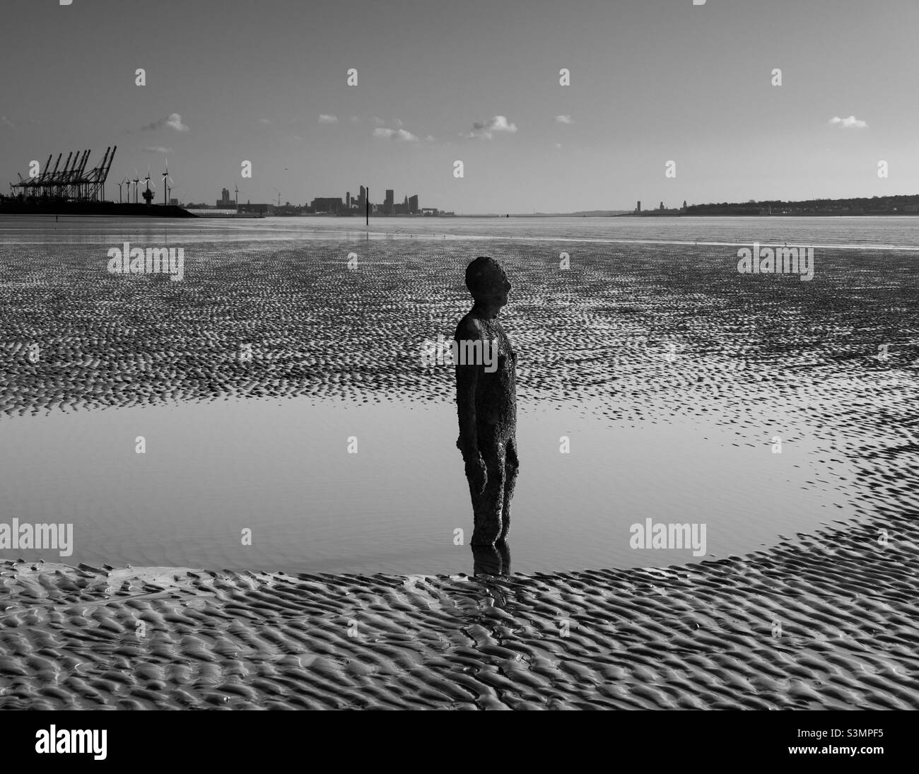 Statue d'Antony Gormley sur la plage de Crosby avec les gratte-ciel de Liverpool en arrière-plan. - Image de stock capturée avec un smartphone