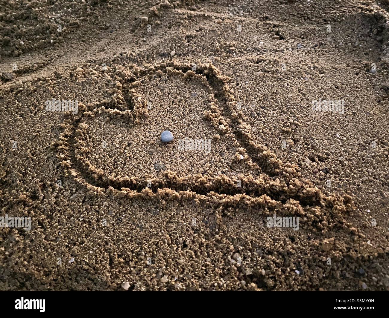Écrire à la main sur le sable en forme de cœur Banque D'Images