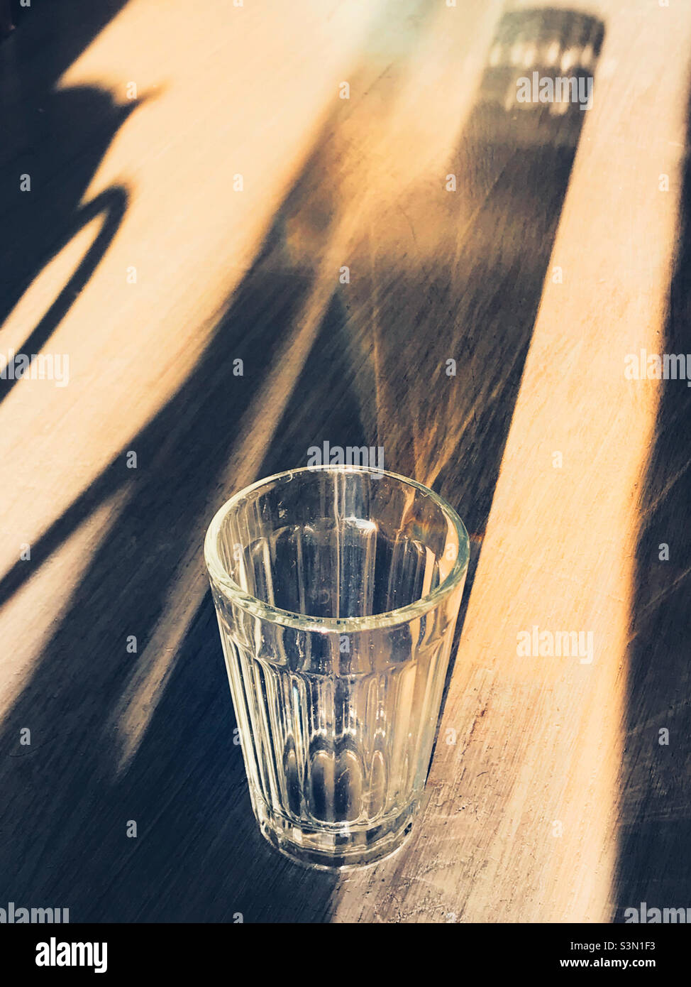 Un verre vide et son ombre en plein soleil Banque D'Images