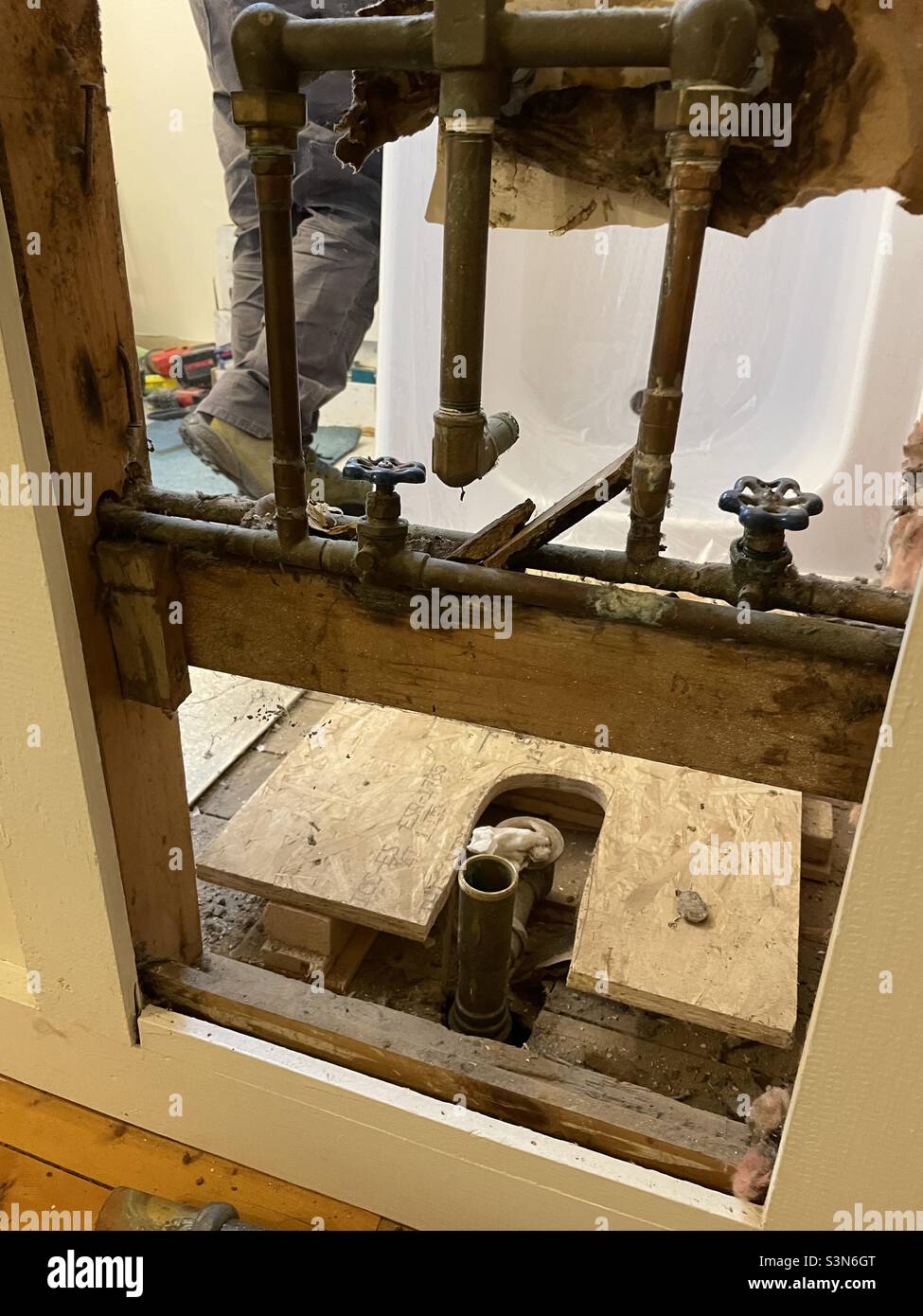 Remplacement de la baignoire dans la vieille maison, installation de plomberie exposée, plate-forme en contreplaqué pour la nouvelle baignoire. Banque D'Images