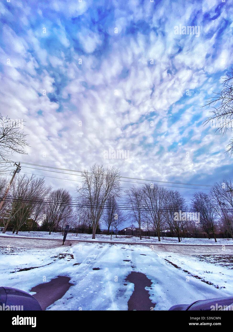 Une vue depuis le pare-brise de ma voiture quand j'ai essayé de conduire dans la neige. L'allée est sur une pente et semble conduire dans le ciel bleu et nuageux. Banque D'Images