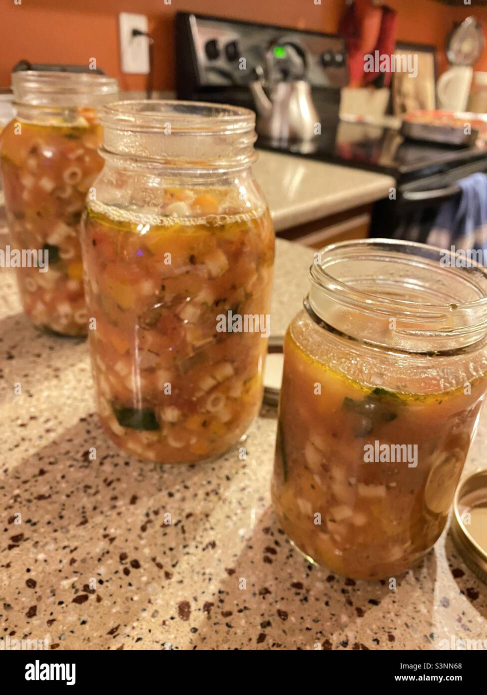 Soupe maison de minestrone dans des pots en verre sur un comptoir de cuisine. - Image de stock capturée avec un smartphone