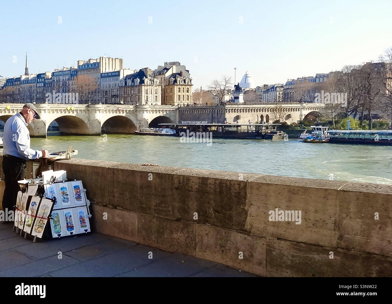 Un artiste peint sur la Seine à Paris, en France, face à la rive gauche, près du Pont neuf (Nouveau pont : 1578-1607), le plus ancien pont sur la rivière. Une statue de bronze du roi Henri IV est à proximité. Banque D'Images