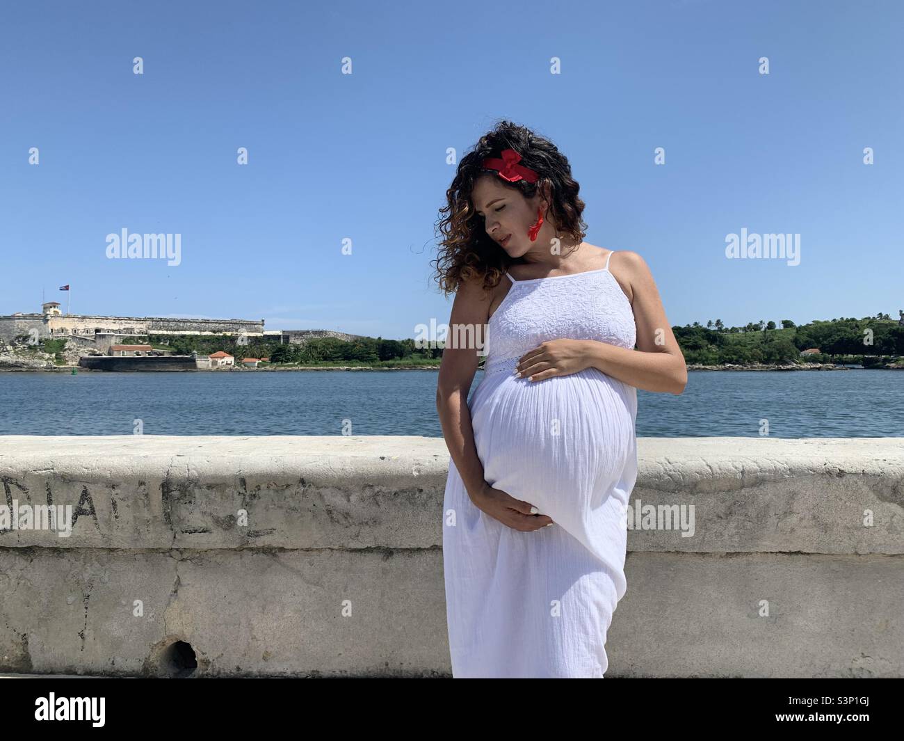 La femme enceinte sur son troisième trimestre caresse son ventre croissant avec tendresse. Les attentes d’une femme enceinte seule. Banque D'Images