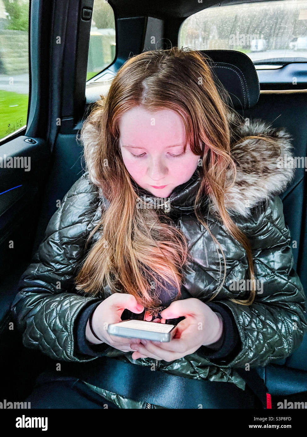 Jeune fille en voiture jouant avec son iPhone d'Apple Banque D'Images