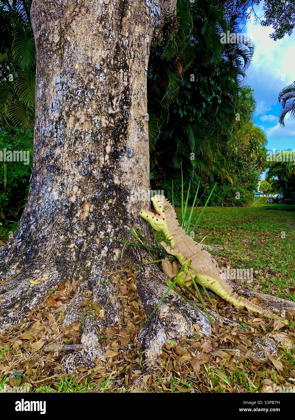 Dinosaure jouet grimpant un arbre. Banque D'Images