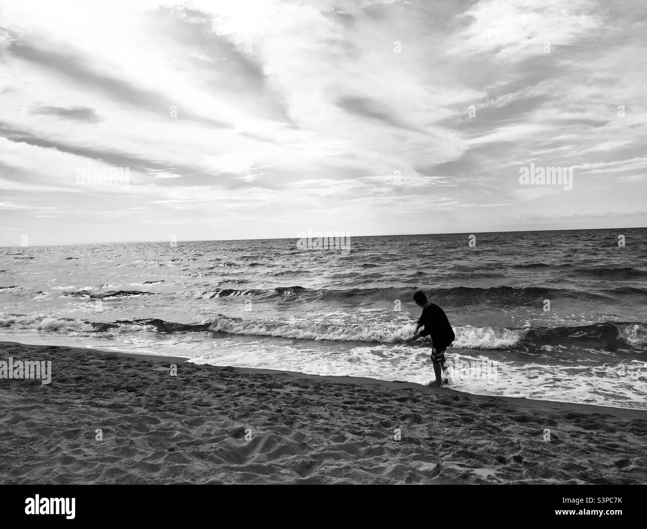 Garçon sautant des rochers à Bothwell Beach, Î.-P.-É., en noir et blanc. Banque D'Images