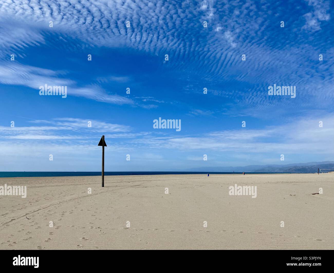 Affiche et empreintes de pas sur la rive déserte de Ventura Beach, Californie, avec l'océan Pacifique en arrière-plan. Ciel bleu avec nuages au-dessus - Image de stock capturée avec un smartphone