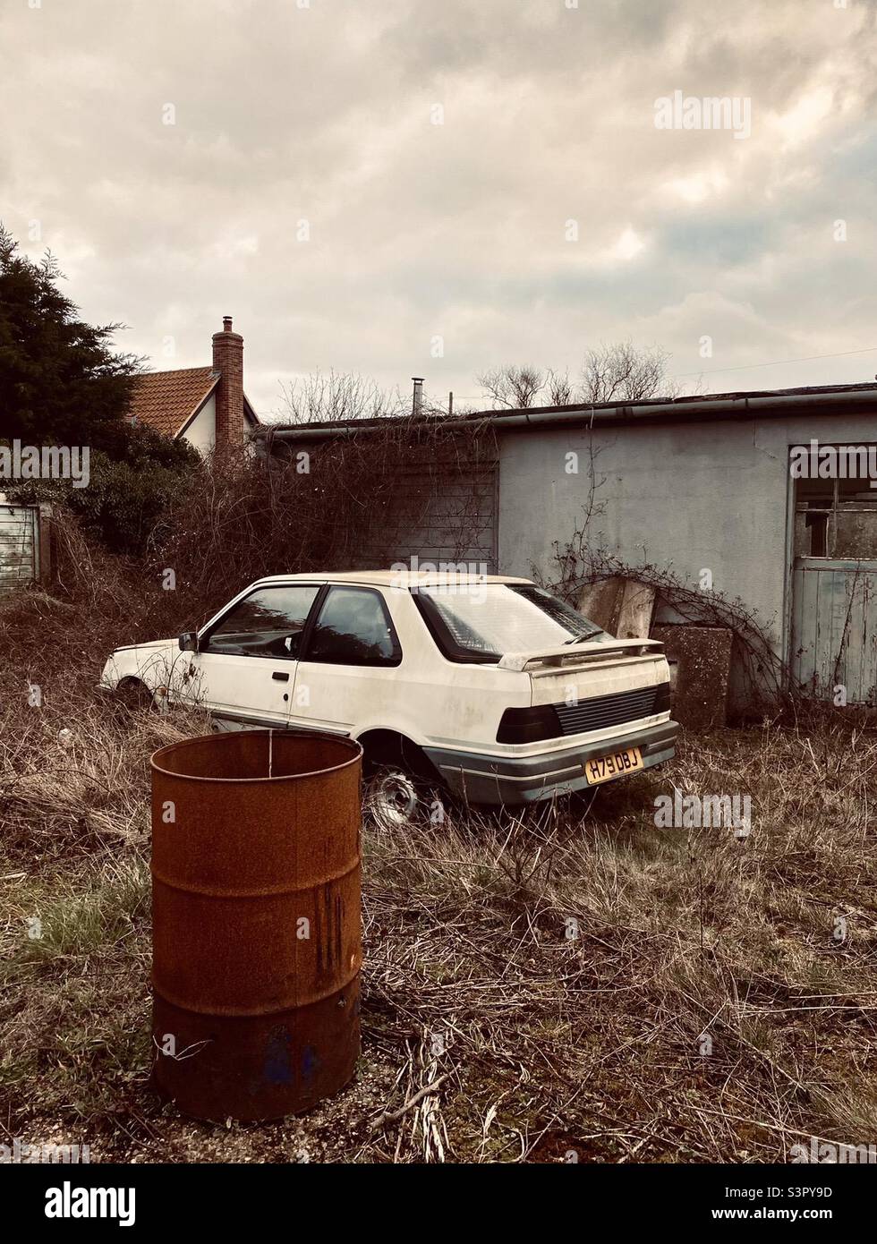 Ancienne Peugeot 309 inutilisée et tambour à huile rouillée Banque D'Images