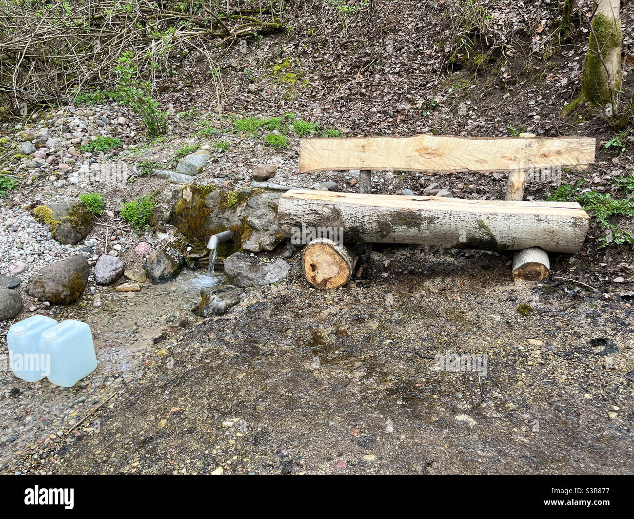 Une source fraîche et fraîche sort du sol. Eau de source fraîche et délicieuse. Source naturelle d'eau souterraine avec espace de copie. Banc de repos Banque D'Images
