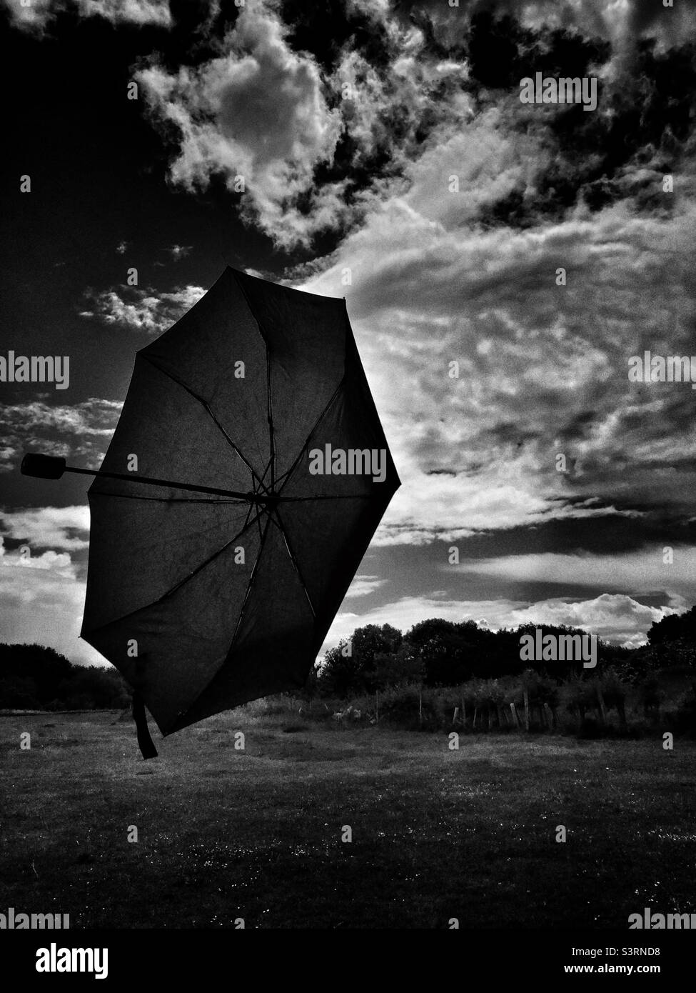 Un parapluie qui est soufflé loin par le vent flottant dans l'air moyen Banque D'Images