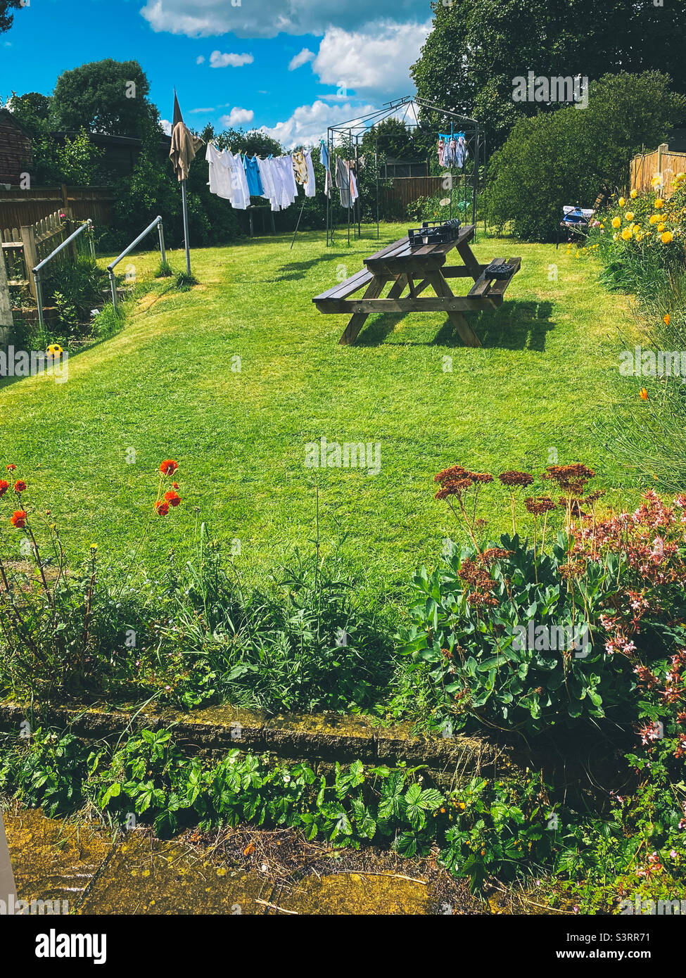 Une vue sur un jardin résidentiel avec une table de pique-nique et un sèche linge sur la ligne de lavage. Banque D'Images