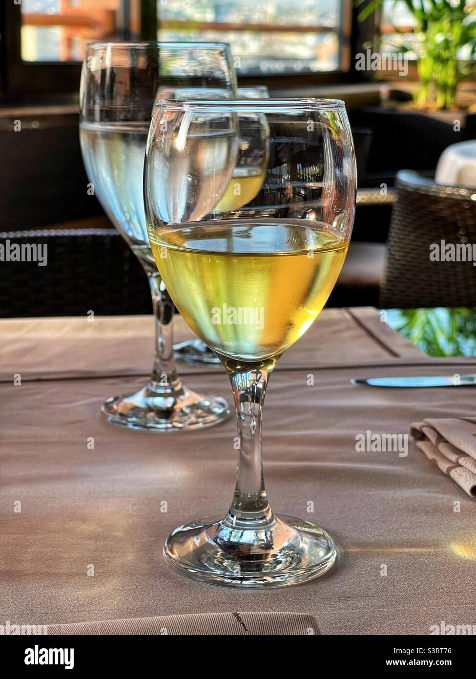 Verre de vin blanc frais sur une table de restaurant au coucher du soleil Banque D'Images