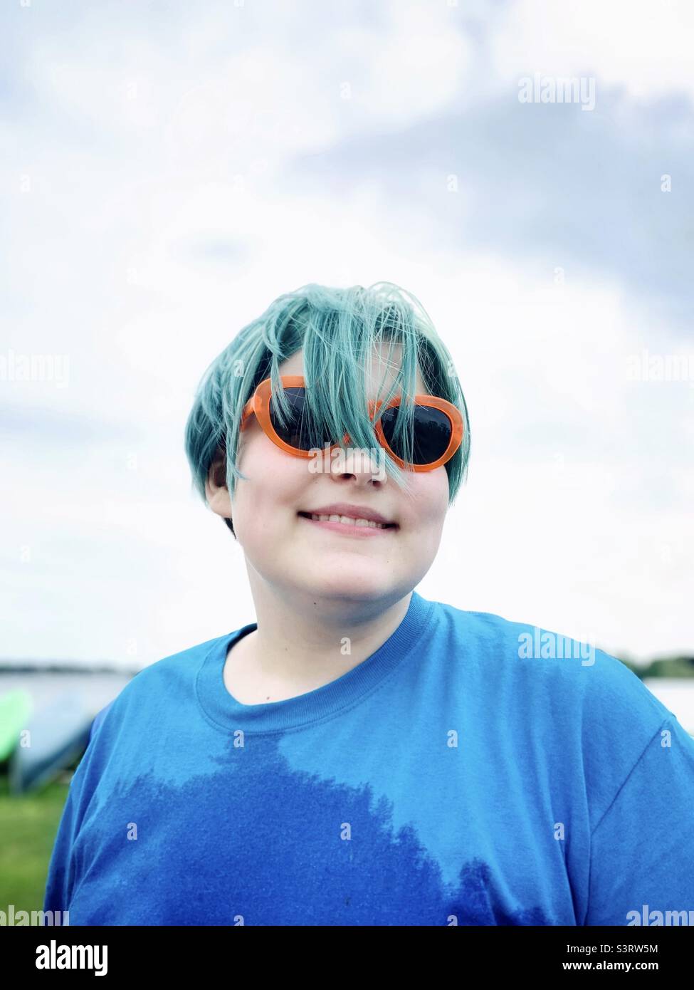 Jeune garçon souriant avec des cheveux colorés et des lunettes de soleil. Banque D'Images