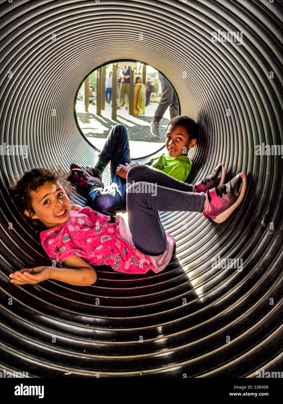 Garçon et fille jouant dans un tube au parc Banque D'Images
