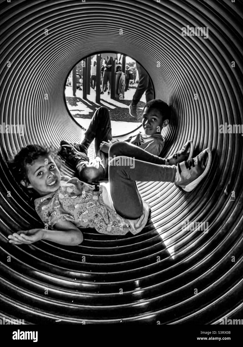 Frère et sœur appréciant jouer dans un tube circulaire au parc local Banque D'Images