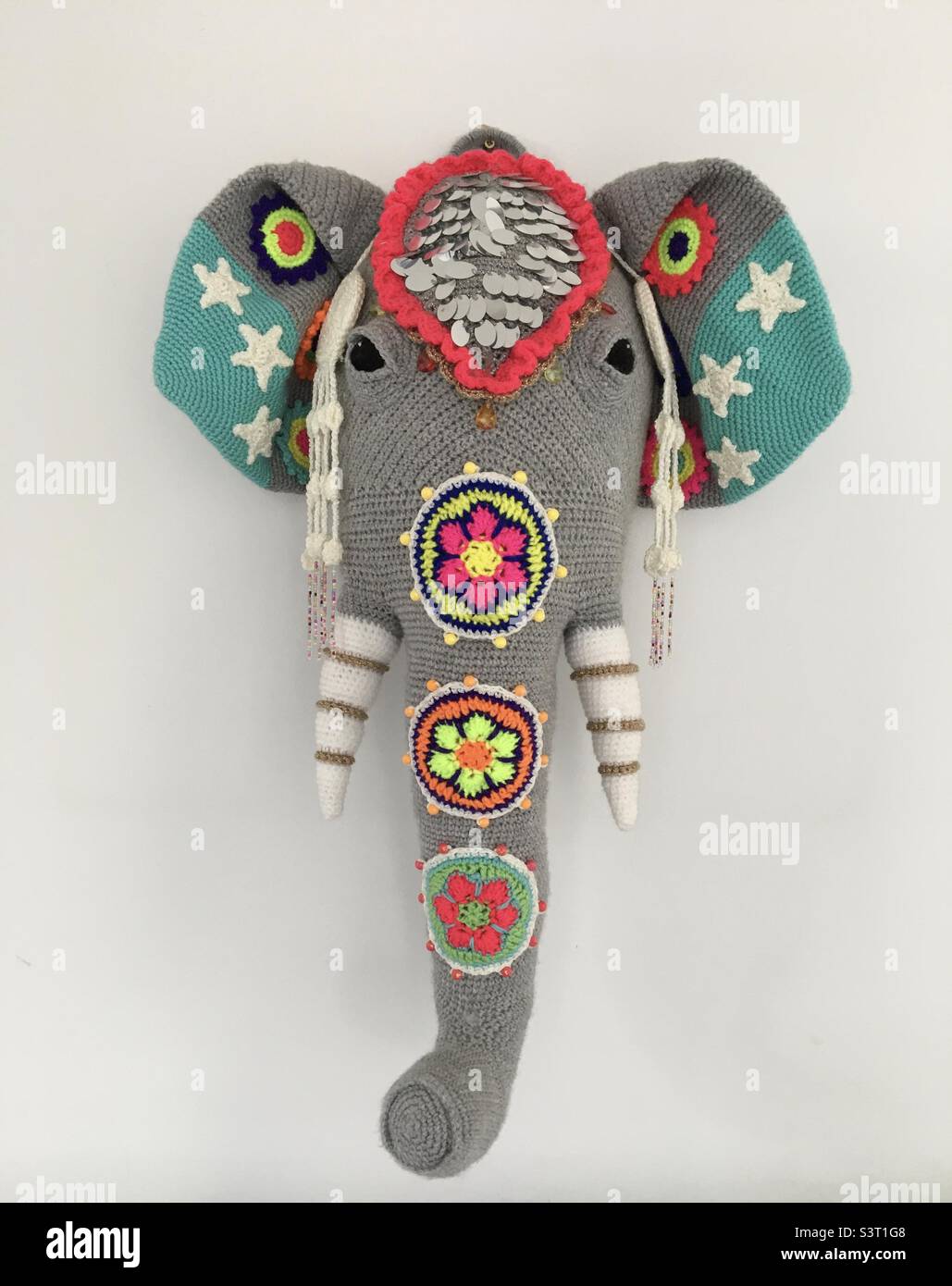 Main tête d'éléphant crochettée avec des décorations sur fond de mur blanc. Banque D'Images