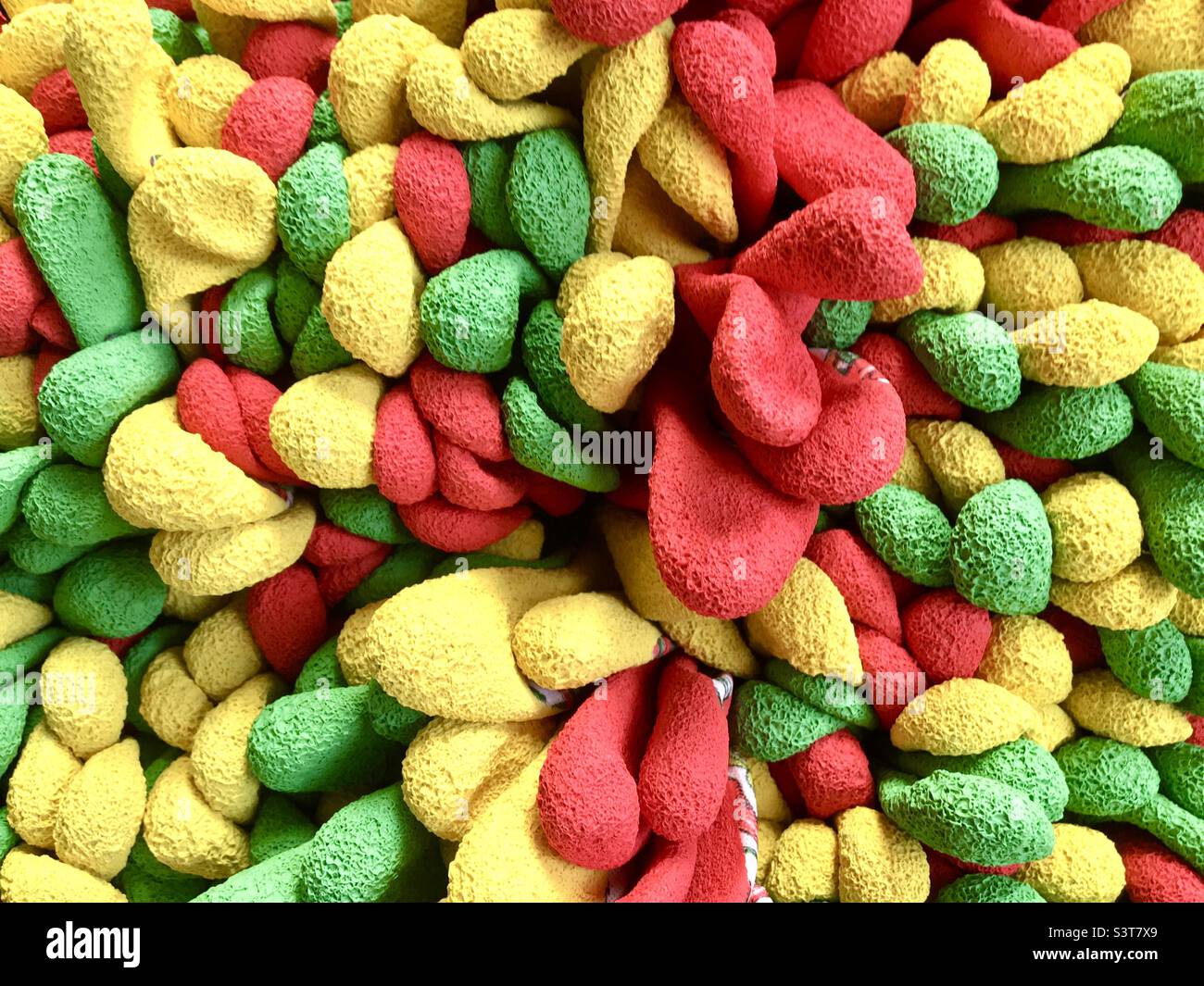 Gants de jardinage rouges, verts et jaunes, doigts sur un présentoir. Banque D'Images