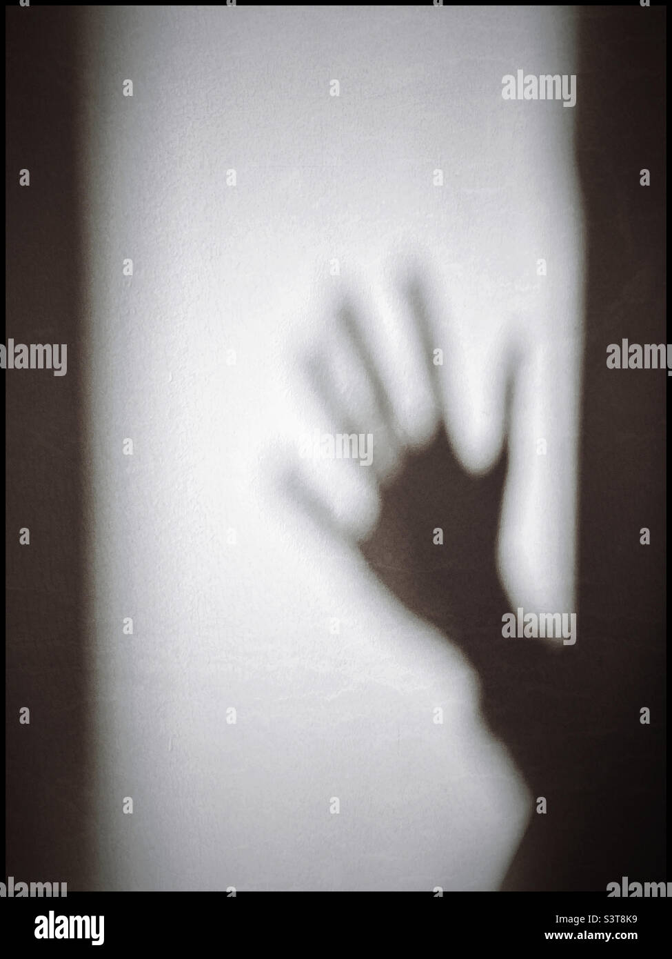 L'ombre d'une main sur un mur blanc. S'agit-il d'une vague amicale ou d'une main attaquante ? Garçon ou fille ? Homme ou femme ? Photo ©️ COLIN HOSKINS. Banque D'Images