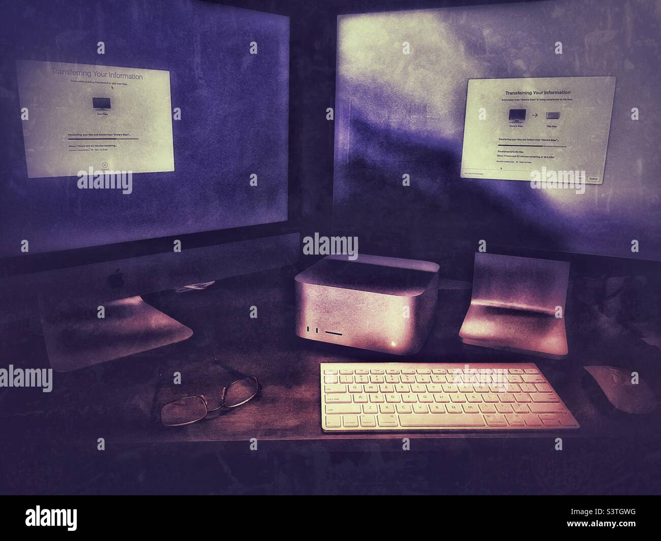 Migration de données vers un nouvel ordinateur Mac Studio Apple installé sur un bureau dans un bureau à domicile de l'Utah, aux États-Unis. Effets lumineux et grunge ajoutés numériquement. - Image de stock capturée avec un smartphone