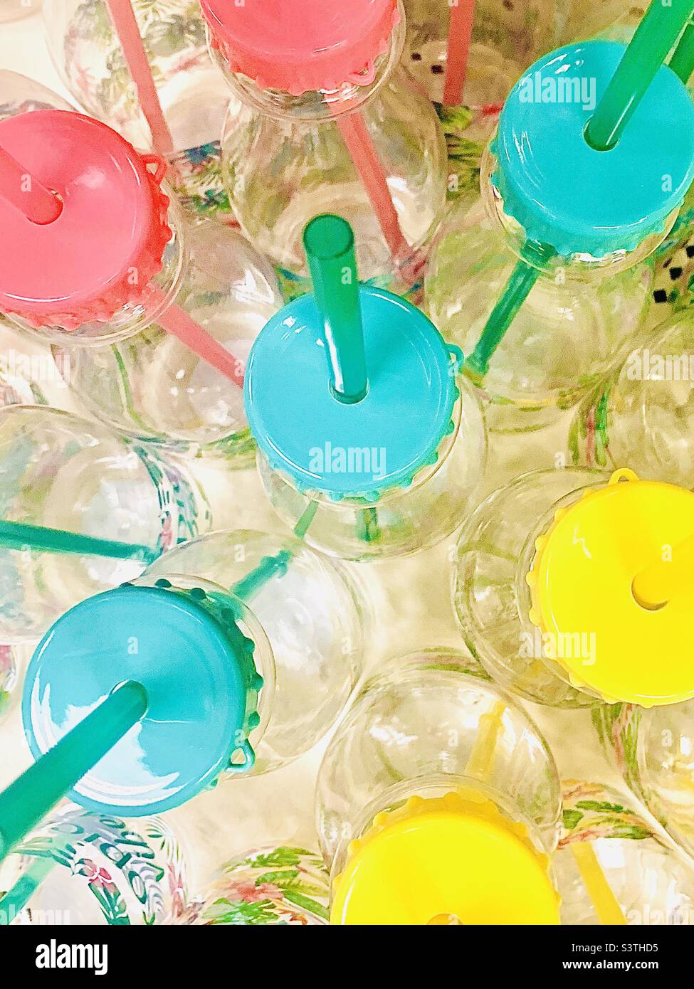 Sélection de jolies bouteilles d'eau transparentes avec couvercles et pailles colorés pastel. Remplit le cadre entier. Banque D'Images