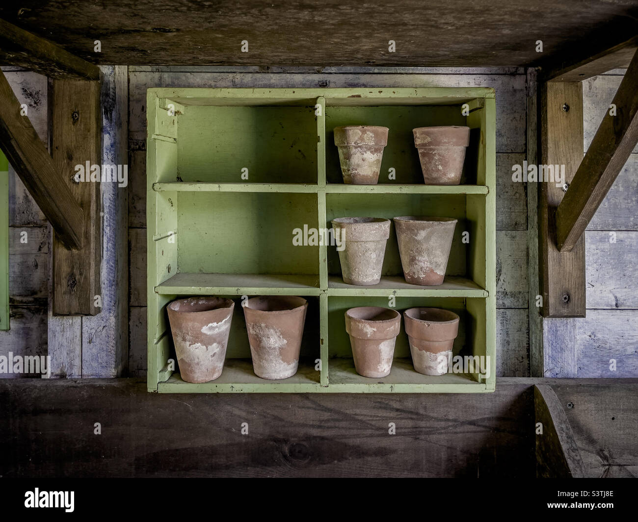 Etagères en bois dans un hangar de pot avec de petits pots de terre cuite Banque D'Images