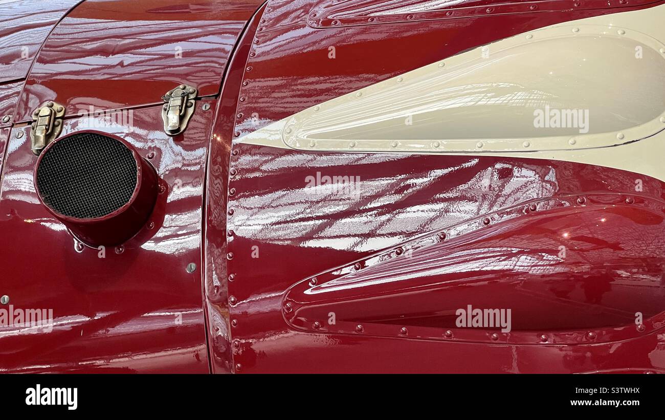 Détail des panneaux métalliques de fuselage d'avion, peints en rouge bordeaux et couleur crème, rivés en place avec des réflexions abstraites. Convient pour l'arrière-plan des graphiques et du texte Banque D'Images