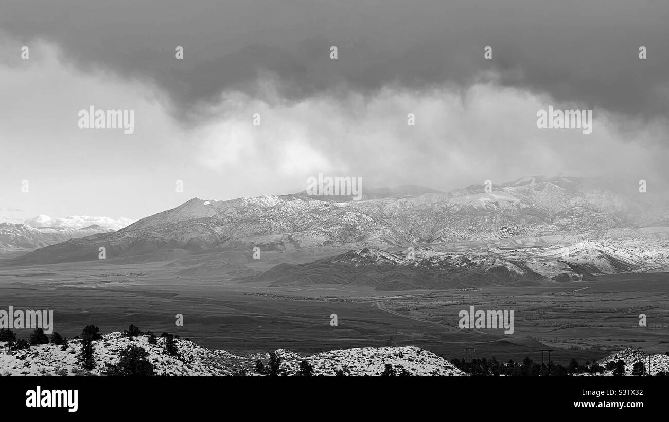 Vue sur les montagnes enneigées près de Bishop, en Californie, avec des nuages de tempête sombre au-dessus. Noir et blanc Banque D'Images