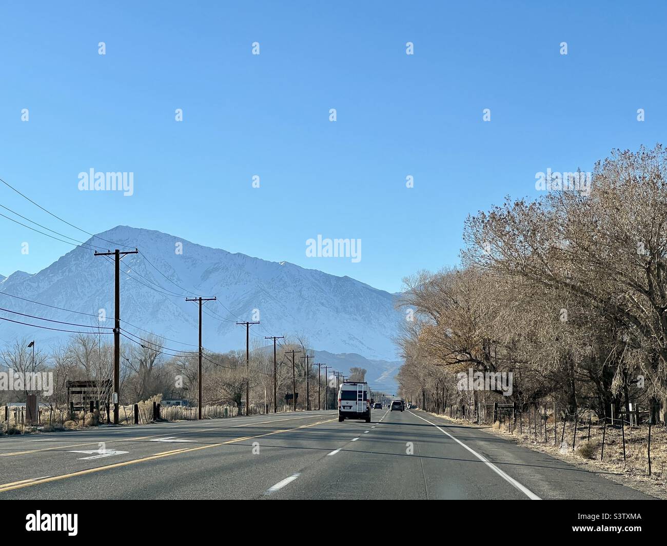 Circulation en direction des montagnes sur la US route 395, après les poteaux de télégraphe à Bishop, Californie Banque D'Images Circulation en direction des montagnes sur la US route 395, après les poteaux de télégraphe à Bishop, Californie Banque D'Images