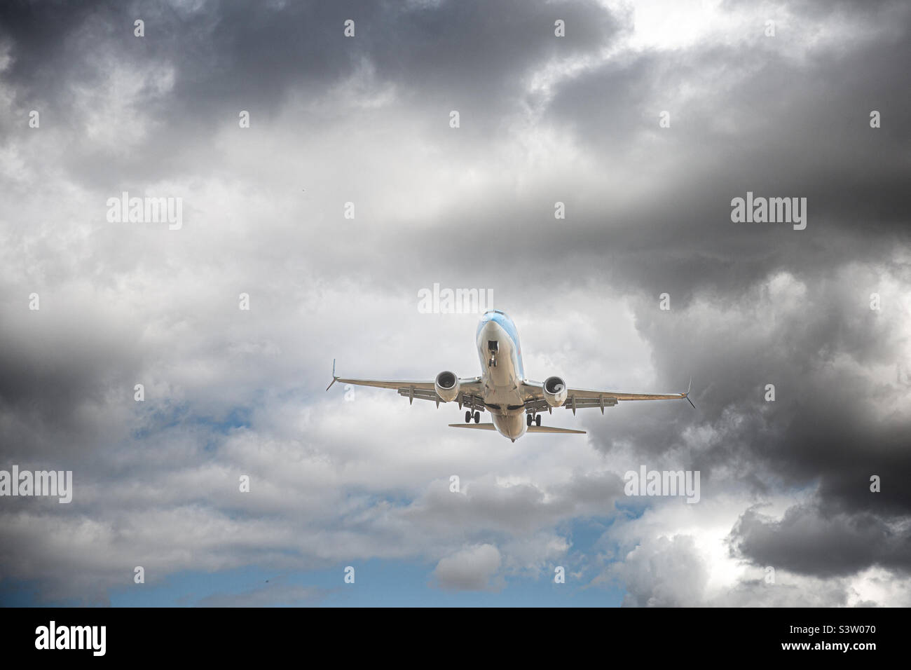 Un avion passager qui dégret ou atterrit et qui survole des turbulences avec des nuages sombres dans un concept de problèmes de voyage Banque D'Images