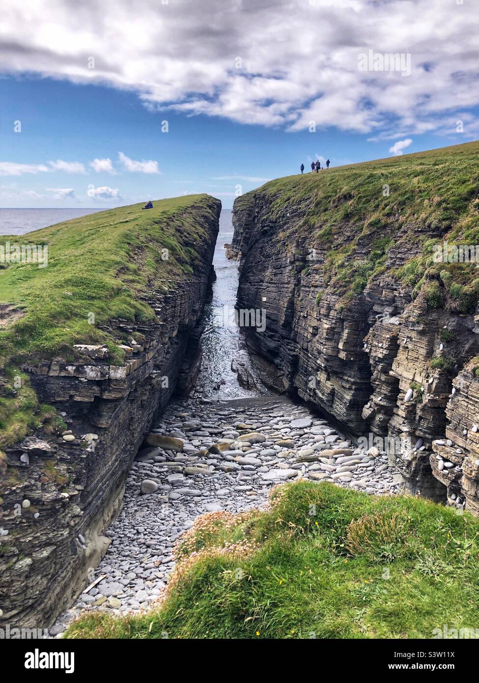 Promeneurs sur le sentier côtier et les falaises du Brough de Birsay, île des Orcades, Écosse Banque D'Images